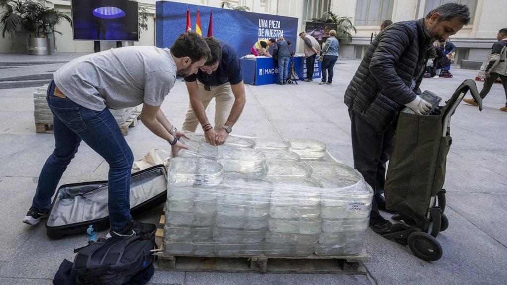 Voluntarios entregan los ladrillos transparentes a un vecino.