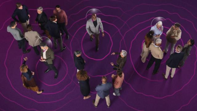 Un hombre usando un audífono rodeada de otras personas