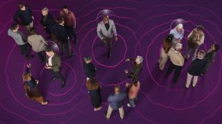 Un hombre usando un audífono rodeada de otras personas