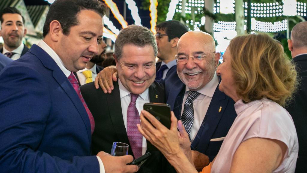 Varios ciudadanos, en la Feria de Abril de Sevilla, enseñan a Page el selfi que se acaban de hacer.
