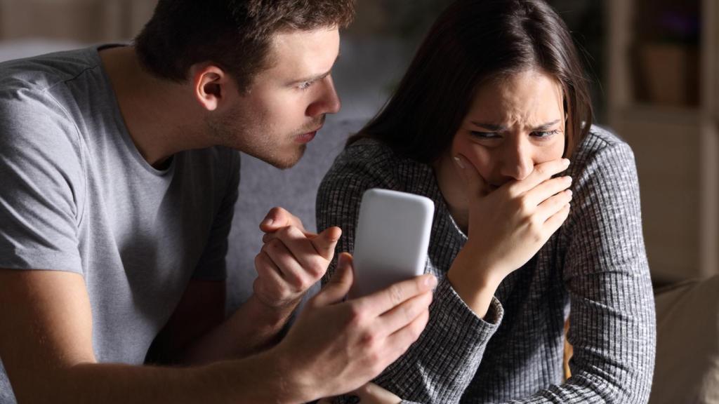 Hombre increpando a su pareja con el teléfono móvil.