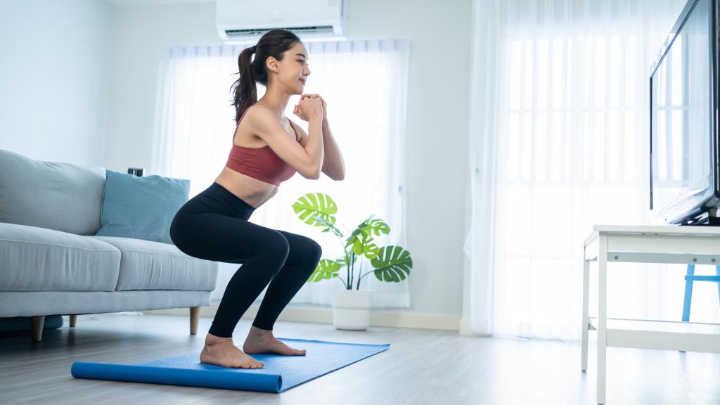 Mujer haciendo sentadillas en casa.
