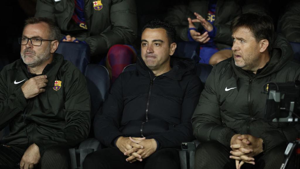 Xavi Hernández sentado en el banquillo junto a su cuerpo técnico