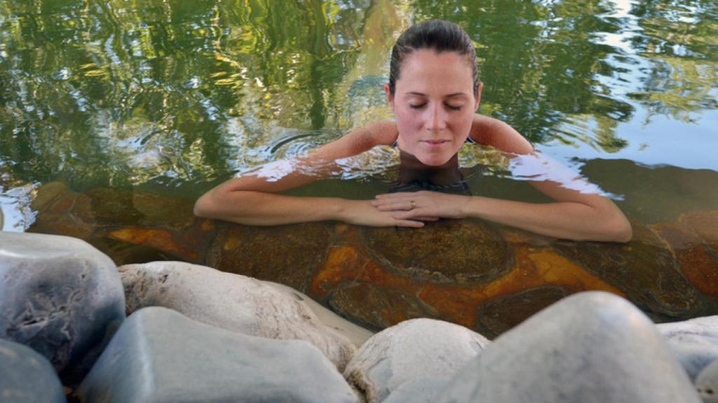 Mujer bañándose en piscina natural.