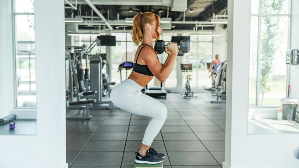 Mujer haciendo sentadillas con pesas.