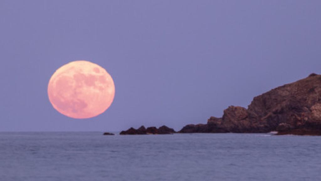 Luna rosa que se eleva sobre el mar Mediterráneo desde la playa de los amigos en la costa brava