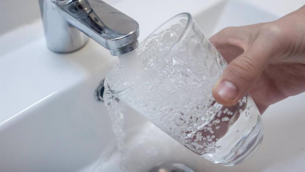 Una persona llenando un vaso de agua del grifo.