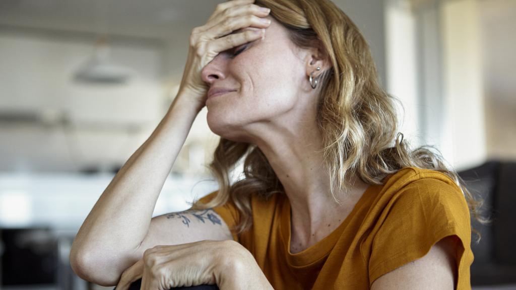 Mujer llorando tapando su rostro.