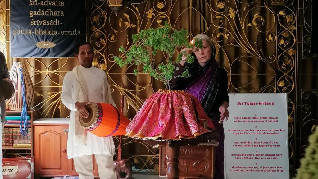 Mujer echándole agua a un árbol como parte de los cánticos