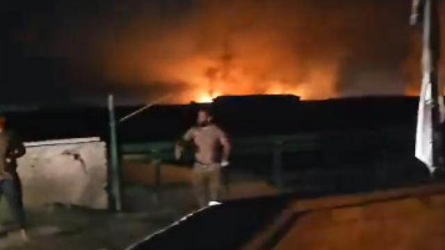 Un soldado iraquí hace señas al camión de bomberos para dirigirlo hacia el incendio en la base militar.