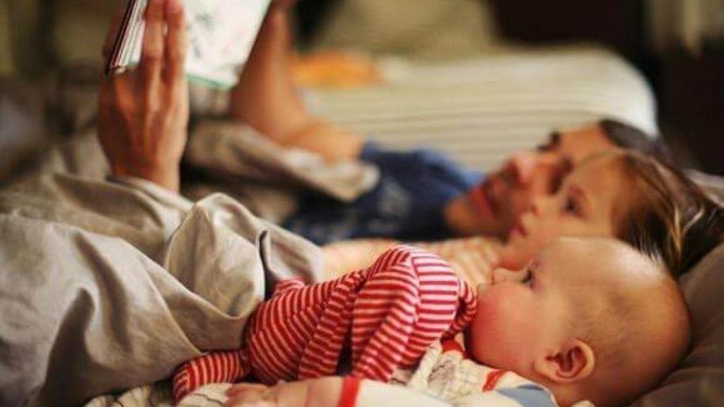 Un padre lee un cuento a sus hijos.