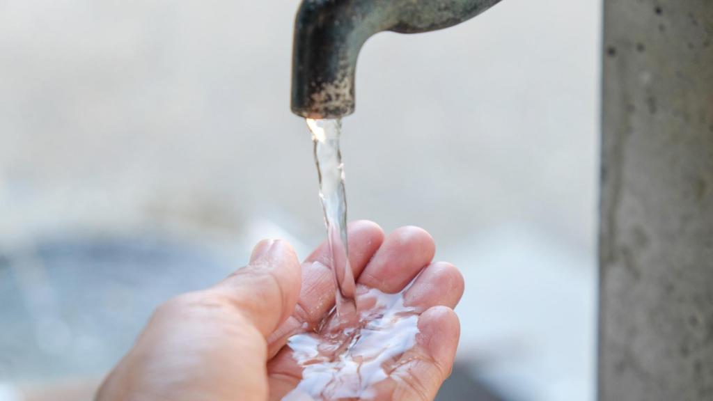 Un ciudadano se refresca en una fuente pública.