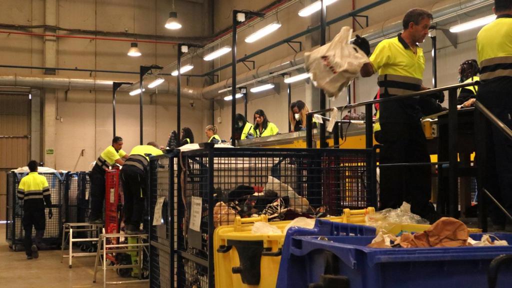 Empleados de la planta clasifican prendas y calzado.