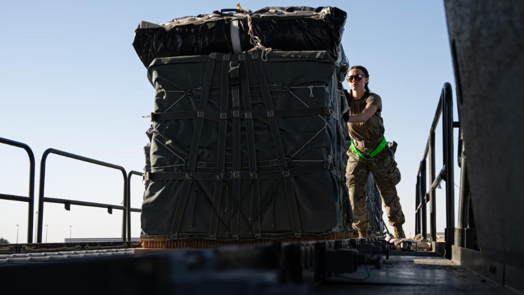 Una militar estadounidense carga ayuda humanitaria en un avión de transporte.