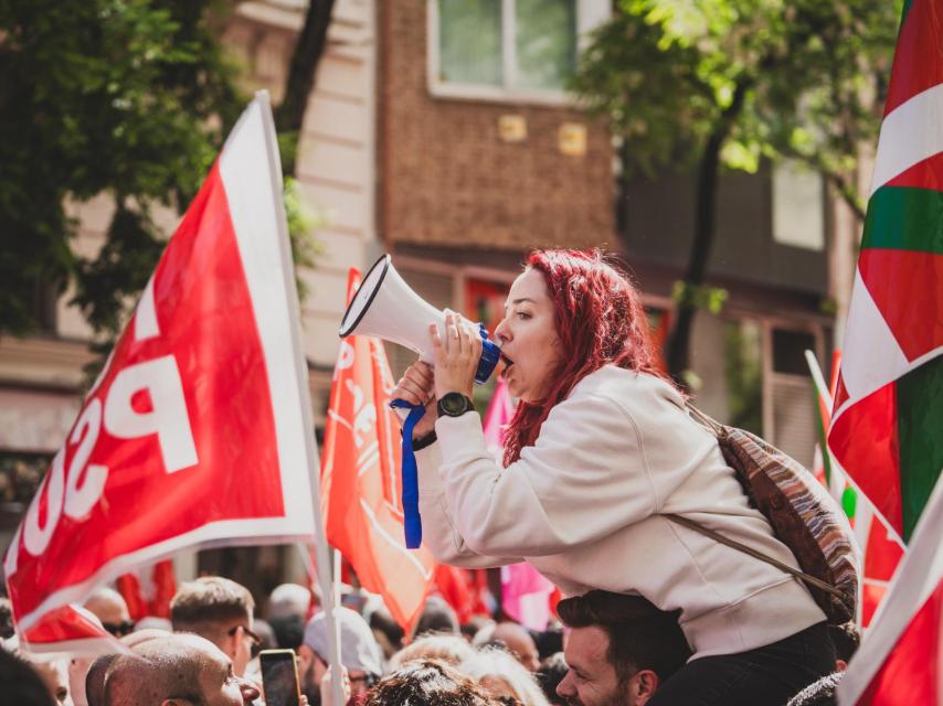 Una manifestante de pelo rosa lanzando consignas en hombros de su amigo.