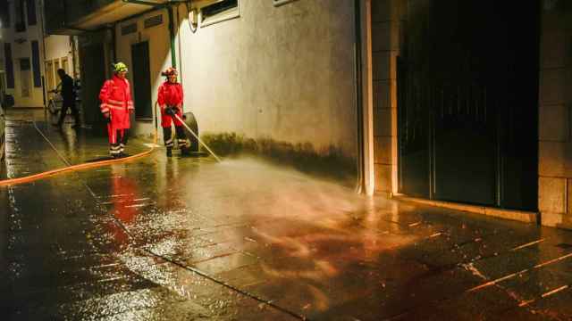 Bomberos limpian la calle de Vilaxoán de Arousa, en Vilagarcía de Arousa (Pontevedra), donde un varón asesinó supuestamente a su cuñado de una puñalada en la tarde de este viernes.