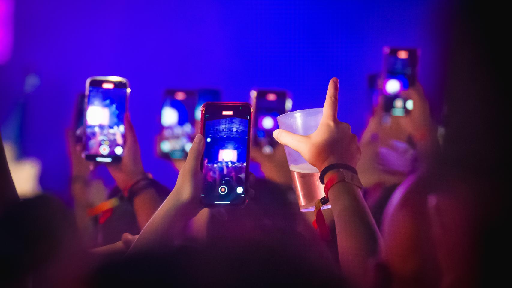 Asistentes a un concierto con vasos en las manos.