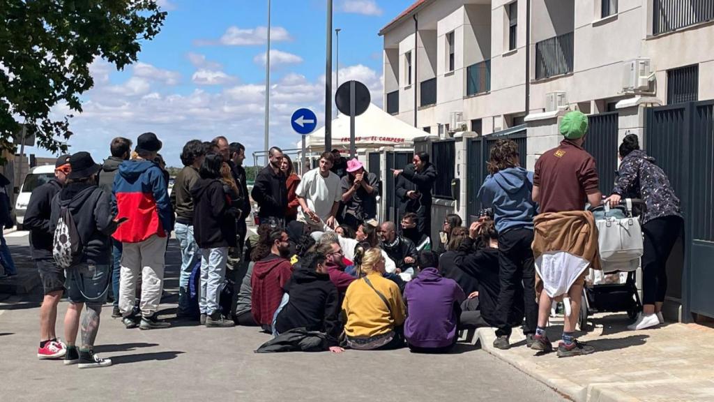 Una mujer intenta acceder con el carrito de bebé a su casa, donde estaban asentados los participantes.