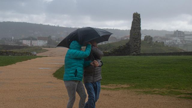 Dos personas se protegen de la lluvia con un paraguas, en la playa de A Lanzada, a 5 de noviembre de 2023.