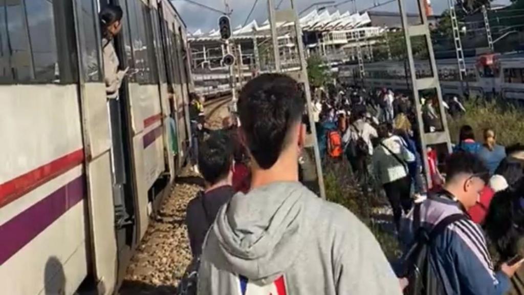 Decenas de pasajeros caminan junto a las vías de tren de Cercanías Madrid.