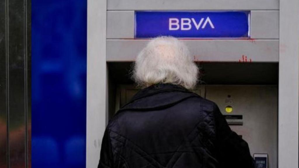 Montaje de dos fotografías de dos personas utilizando sendos cajeros de Sabadell y BBVA.