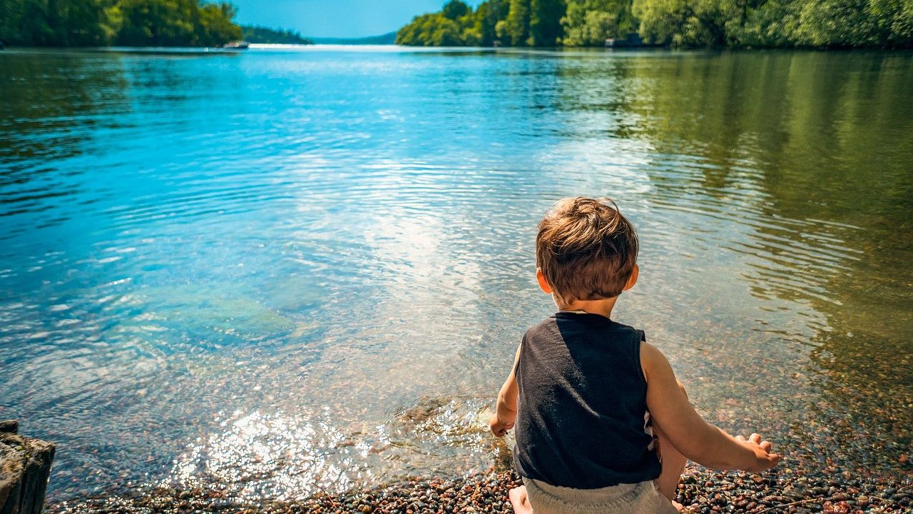 Un niño jugando al borde de un lago.