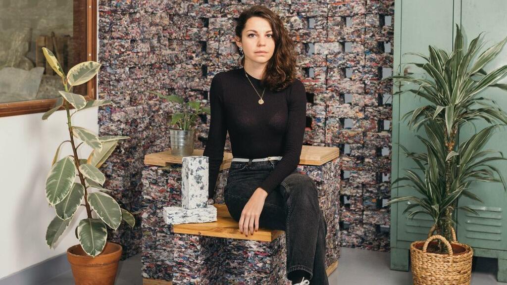 Clarisse Merlet, fundadora de FabBRICK, sobre una silla hecha de ropa usada.