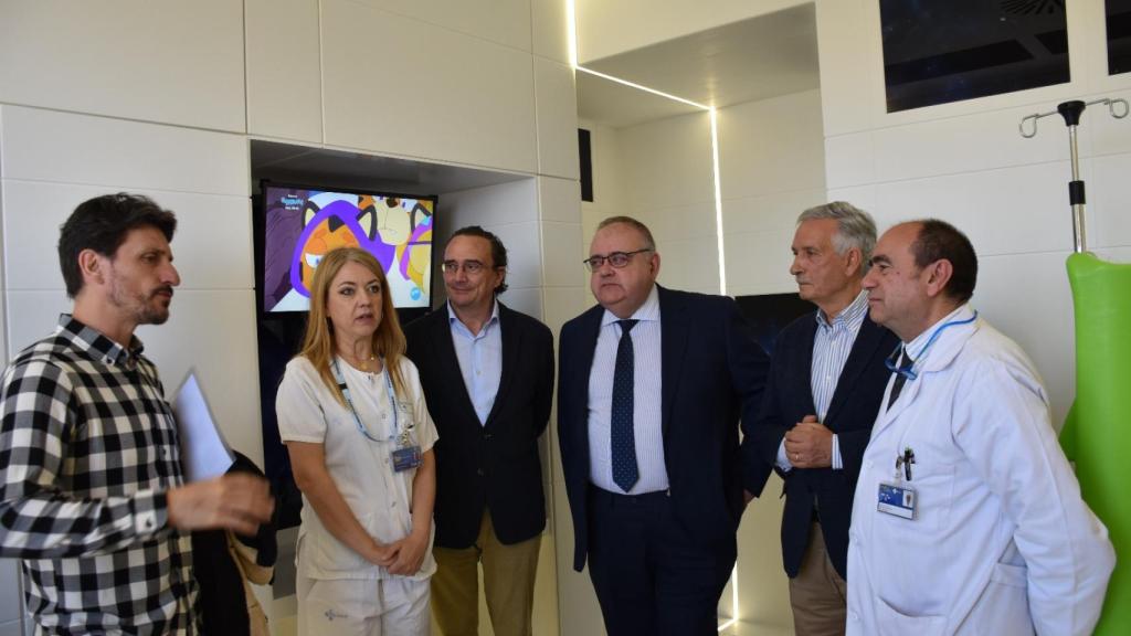 El consejero, Alejandro Vázquez, y el presidente de la Asociación Española Contra el Cáncer en Valladolid, Artemio Domínguez, atienden a uno de los arquitectos que ha diseñado la habitación
