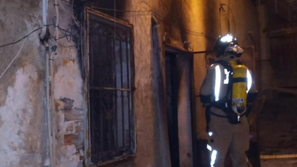 Bombero ante la vivienda incendiada.