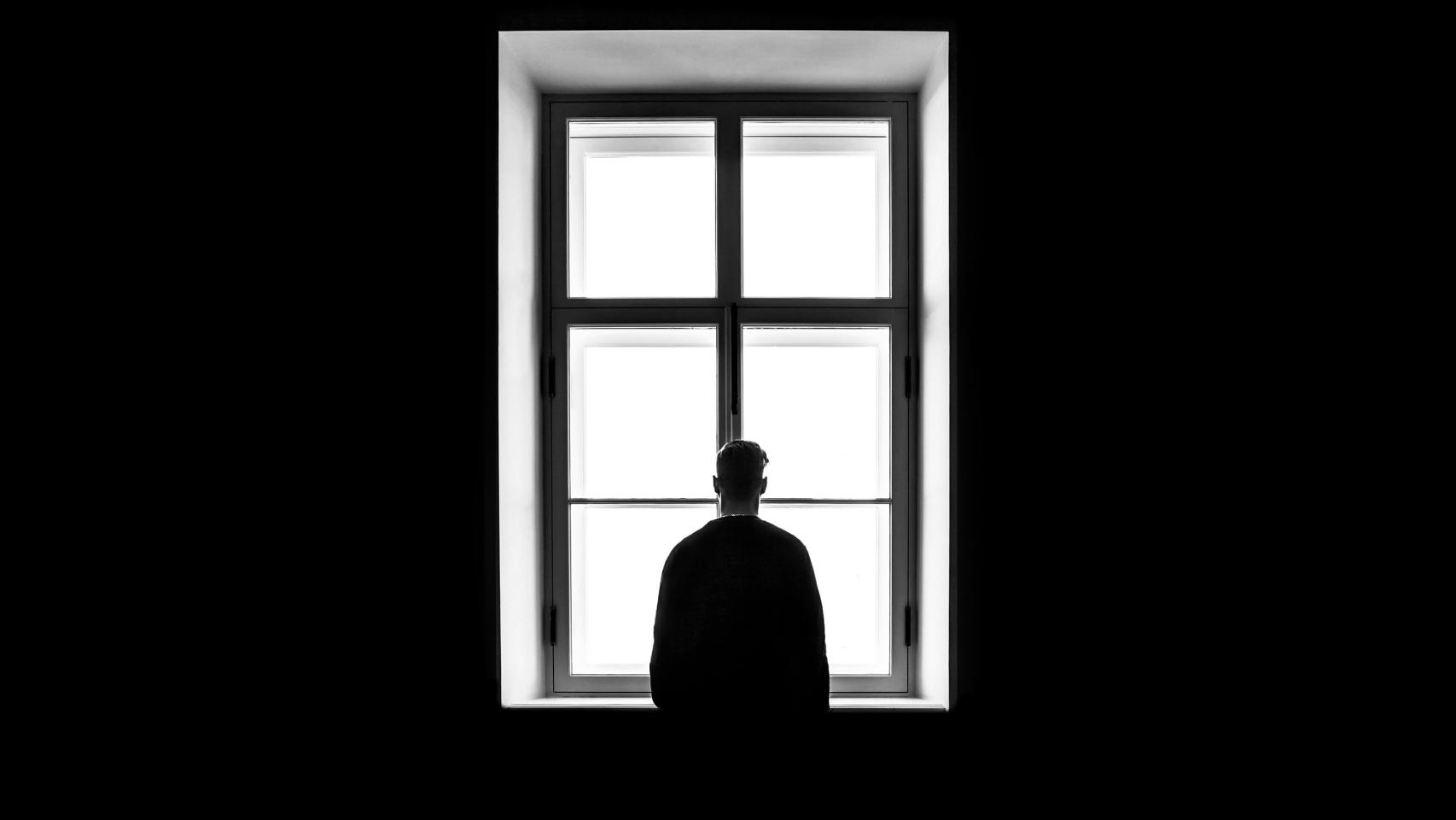 Una imagen de archivo de un joven mirando solo por la ventana.