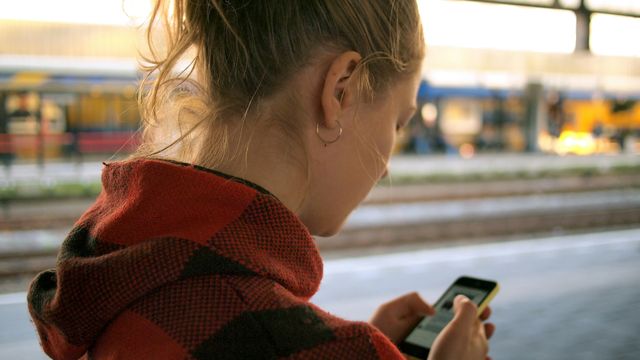 Una joven sosteniendo un teléfono móvil.