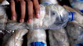 Un policía sostiene una botella de agua con una cacatúa de cresta amarilla introducida en su interior para su comercio ilegal.