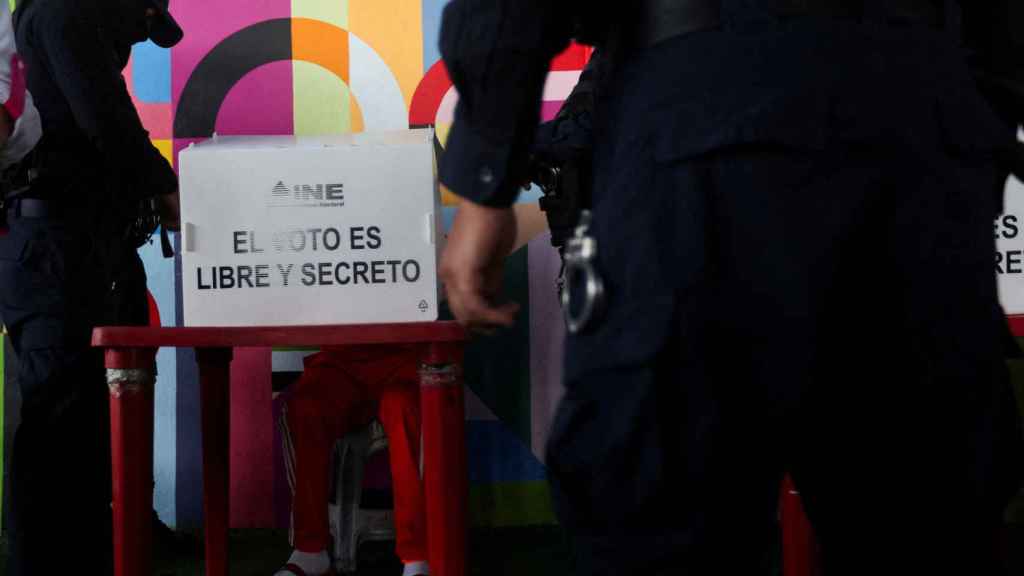 Funcionarios de prisiones vigilan mientras los reclusos votan en la prisión de Barrientos (Tlalnepatla).