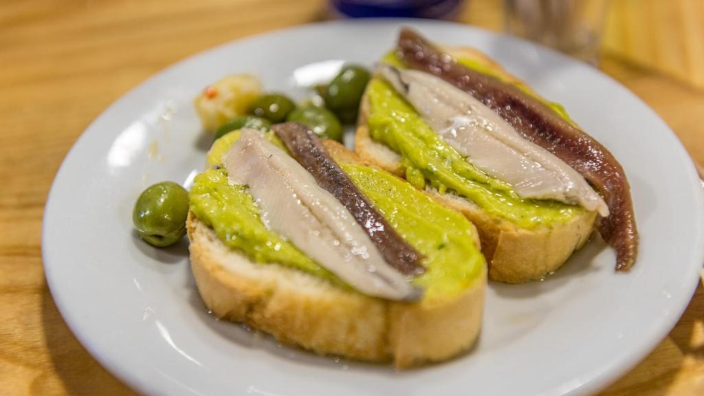 Matrimonio de anchoa y boquerón sobre una rebanada de pan con aguacate