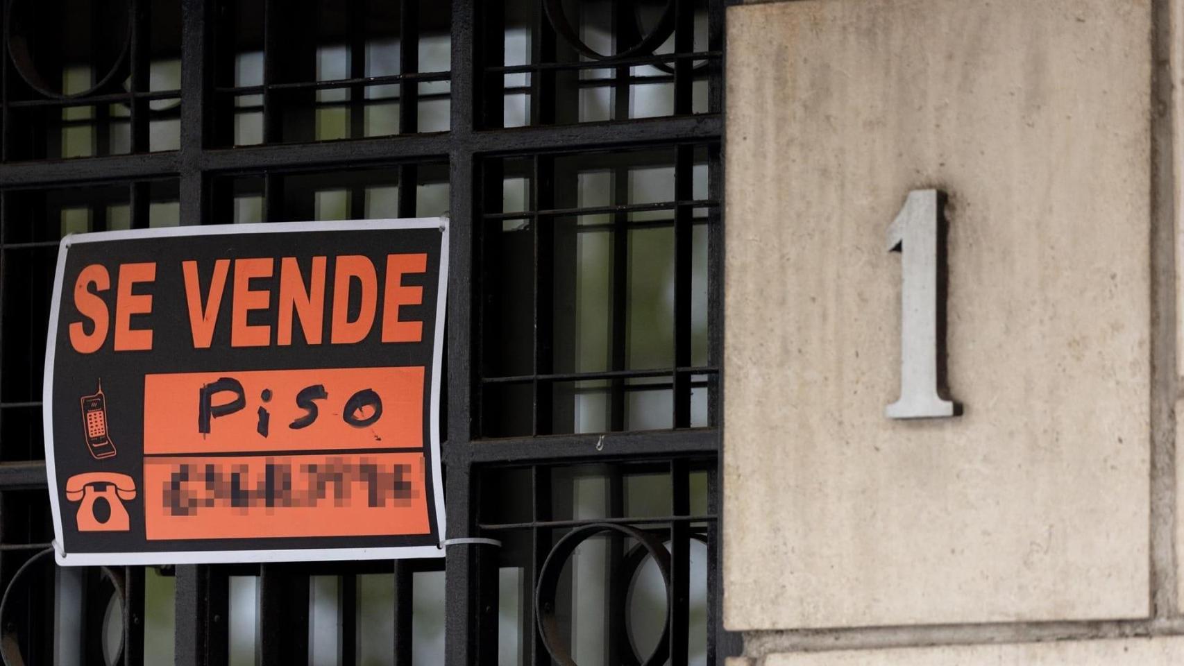 Vista de un cartel de Se vende en un portal de un edificio.