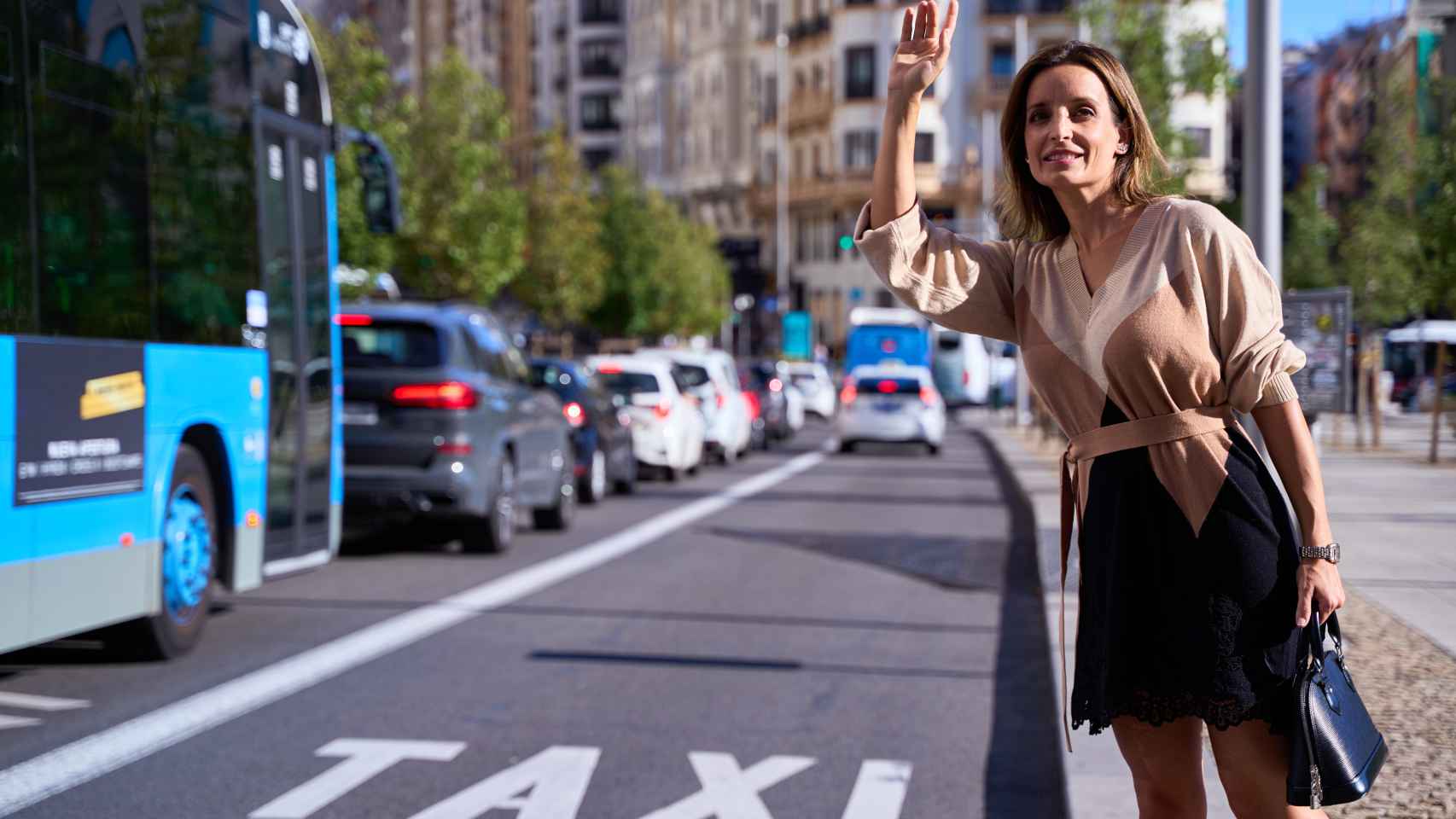 Una mujer pide un taxi en la calle.