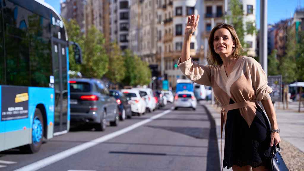 Una mujer pide un taxi en la calle.