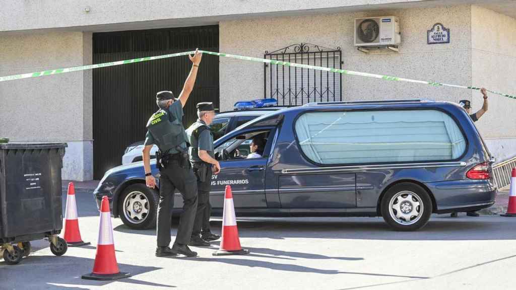 Tres agentes de la Guardia Civil facilitan el paso de un coche fúnebre a la Calle Alfredo Nobel.