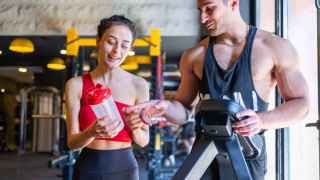 Foto de archivo de una hombre y una mujer tomando suplementos en un gimnasio. iStock