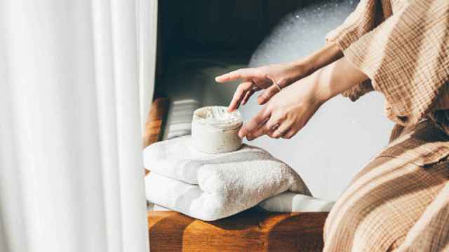Mujer cogiendo crema para aplicársela en la piel