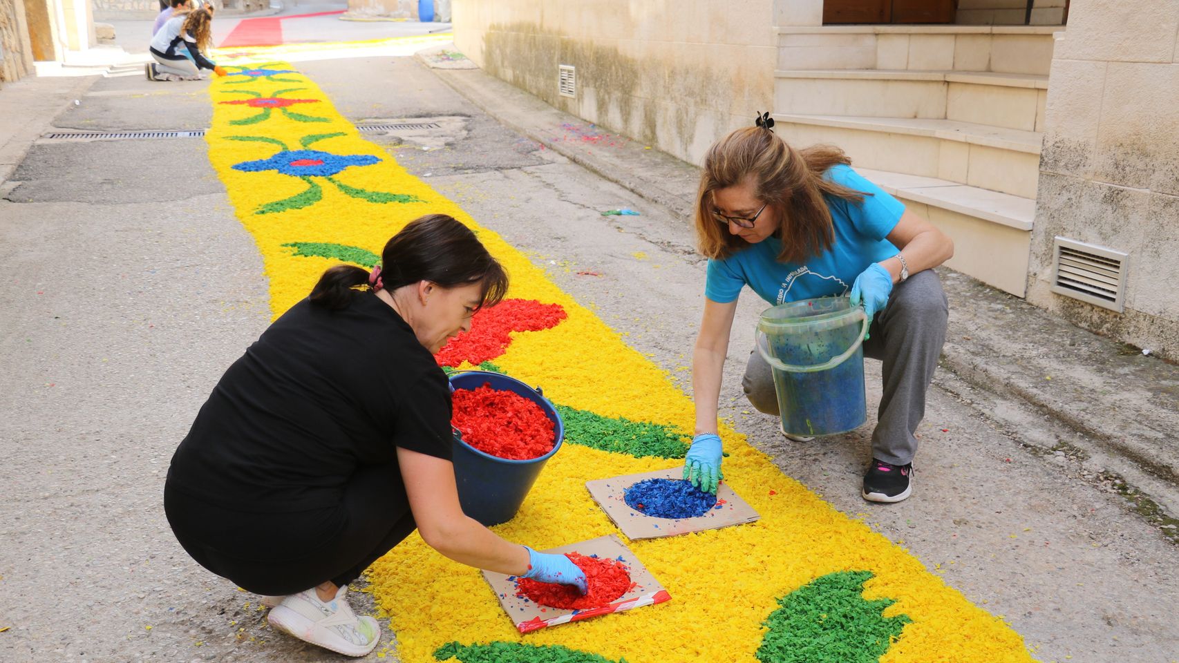 Dos vecinas decorando las alfombras de flores.