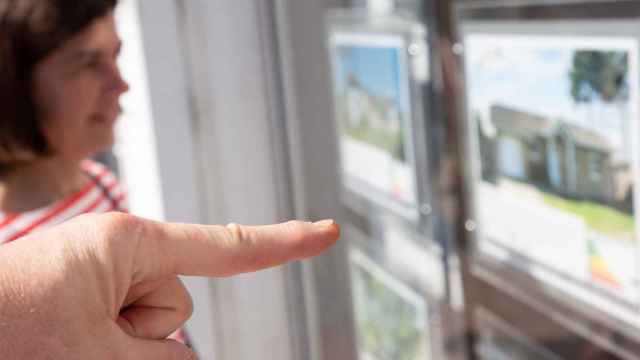 Una pareja mira el escaparate de una agencia inmobiliaria.