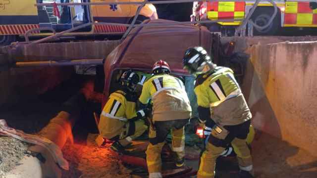 Los bomberos, este domingo, tratando de liberar los cuerpos de los dos fallecidos en el siniestro.