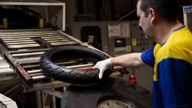 Imagen de un operario con un neumático de moto.