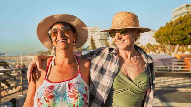 Mujeres sonriendo mientras pasean por la costa en verano.