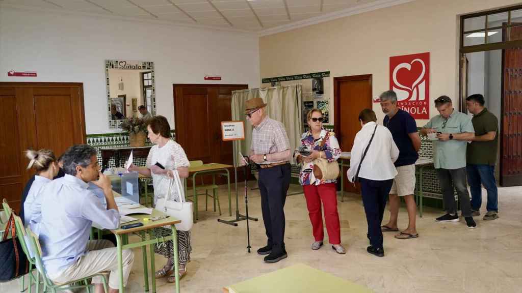 Varias personas hacen cola para votar en un colegio electoral.