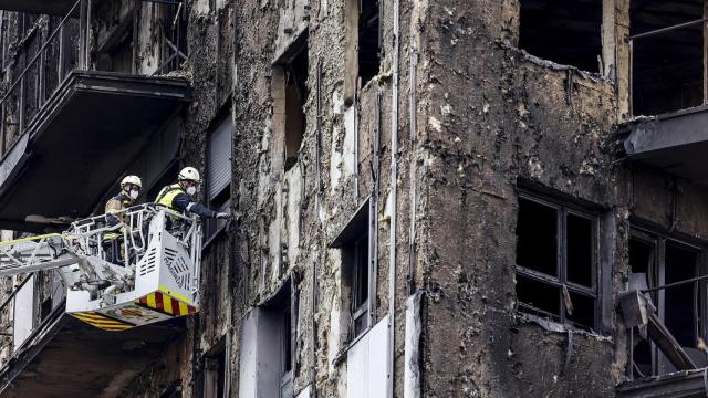 Bomberos en una grúa sanean la fachada quemada, a 26 de febrero de 2024, en Valencia, Comunidad Valenciana (España).