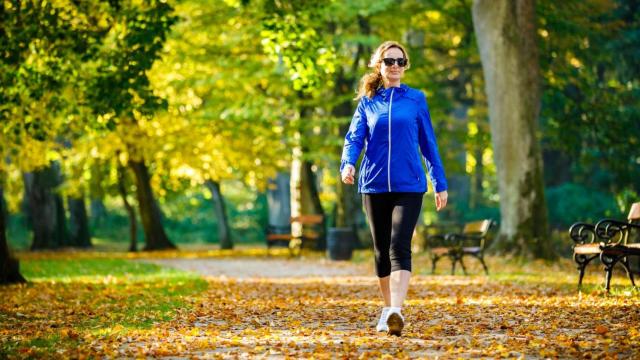 Mujer caminando con ropa de deporte por un parque.