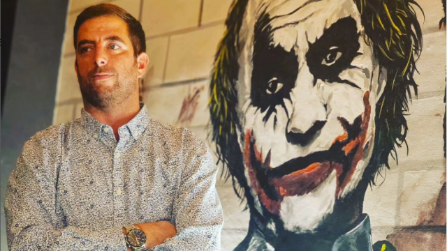 Sayo frente a un dibujo del Joker.