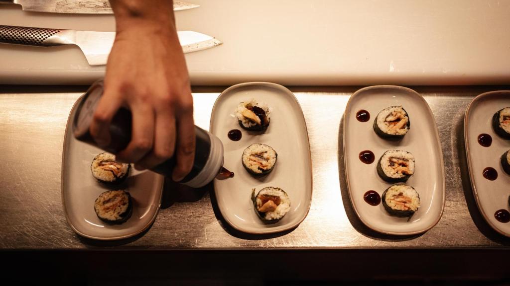 El chef prepara las piezas de sushi frente a los comensales.